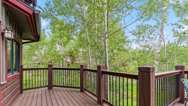 A wooden deck with a railing, surrounded by trees. - Stunning 5BR Family Lodge—Hot Tub, Huge Deck & Mountain Views (Silverthorne)