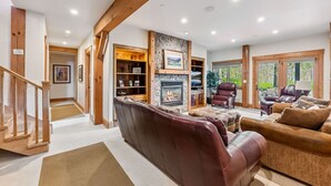 A cozy living room with a fireplace, leather sofas, and a wooden staircase. - Stunning 5BR Family Lodge—Hot Tub, Huge Deck & Mountain Views (Silverthorne)