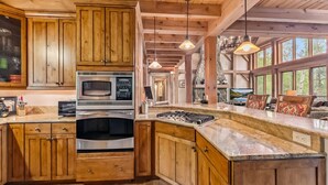 A spacious kitchen with wooden cabinets, a built-in oven, and a large island with a stove. - Stunning 5BR Family Lodge—Hot Tub, Huge Deck & Mountain Views (Silverthorne)