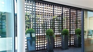Une chambre moderne dotée d’une grande fenêtre, d’un plancher en bois et d’une cloison en métal noir agrémentée de plantes.