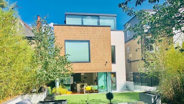 Une maison moderne dotée d’une véranda en verre, d’un coin repas et d’une cuisine ouverte.