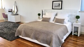 Une chambre à coucher moderne avec un grand lit, un bureau et un ordinateur.