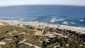 Un paysage côtier caractérisé par une plage de sable et une végétation luxuriante.