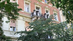 Un edifici de diversos pisos amb façana de maó vermell, balcons ornamentals i grans finestres.