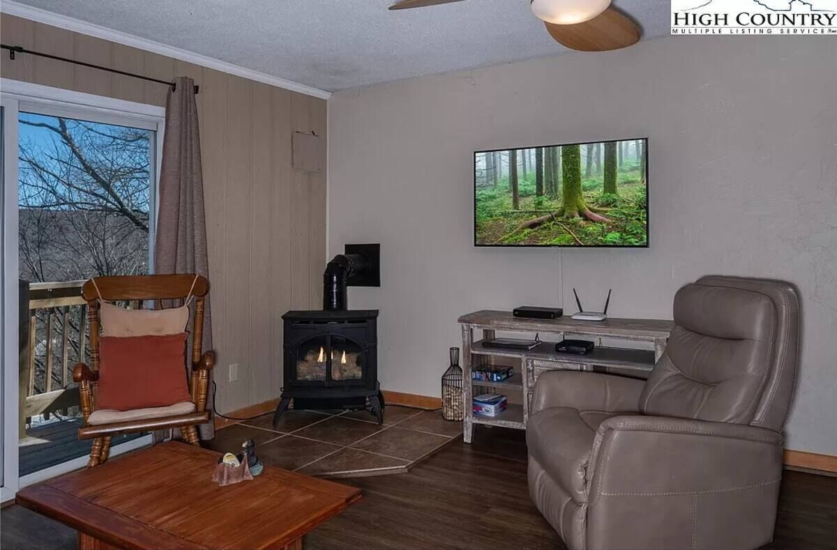 Una sala de estar acogedora con chimenea, un sillón cómodo, un sofá y un televisor montado en la pared.