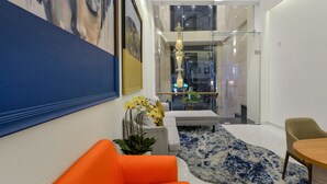 A modern interior with a glass partition, a sofa, a table, and a decorative plant.