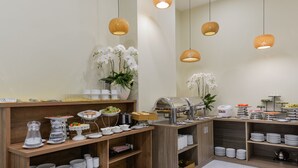 A buffet setup with various food stations, including a coffee machine and a fruit display.