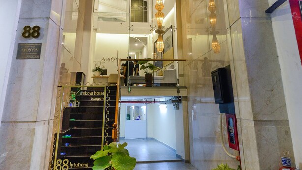 The entrance to Akoya Hotel with a modern design, including a glass facade, a staircase leading to the upper floor, and a sign above the entrance.