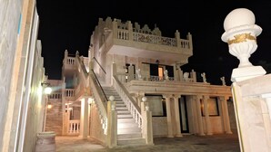 Ein imposantes, mehrstöckiges Gebäude mit einer markanten Treppe und Balkonen, das klassische architektonische Elemente aufweist.