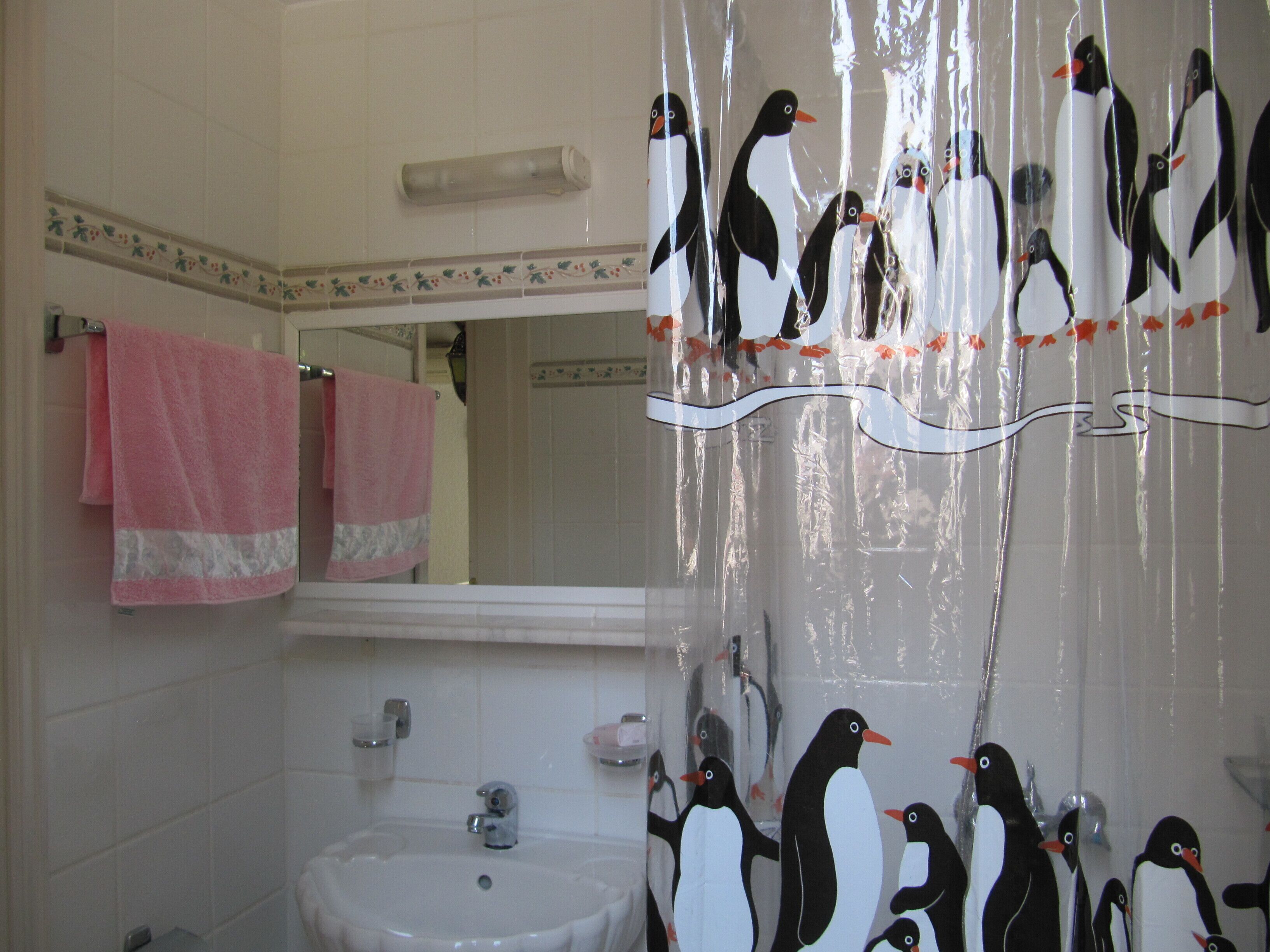 Une salle de bain avec un lavabo, un miroir et des serviettes roses.