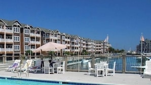 Une piscine entourée de bâtiments à plusieurs étages dotés de balcons, avec des chaises longues et des parasols à proximité.