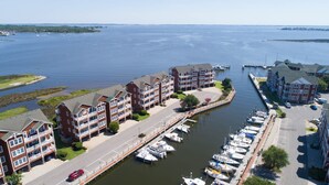 Un port de plaisance où sont amarrés des bateaux, entouré d’immeubles à plusieurs étages dotés de balcons, d’une route et offrant une vue dégagée sur l’eau.