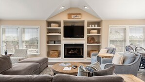 A modern living room with a fireplace, comfortable seating, and a television. - Banks Retreat: Private Pool, Hot Tub, Dog-friendly, 700 feet to Beach Access (Corolla)