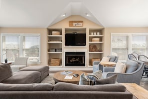 A modern living room with a fireplace, comfortable seating, and a television.