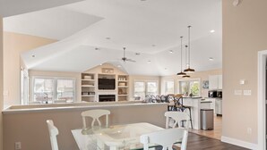 A spacious kitchen with modern appliances, a dining area with a glass table, and a cozy seating area with striped cushions. - Banks Retreat: Private Pool, Hot Tub, Dog-friendly, 700 feet to Beach Access (Corolla)