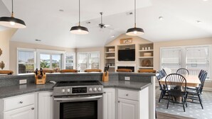 A modern kitchen with a central island, built-in oven, and a dining area with a table and chairs. - Banks Retreat: Private Pool, Hot Tub, Dog-friendly, 700 feet to Beach Access (Corolla)