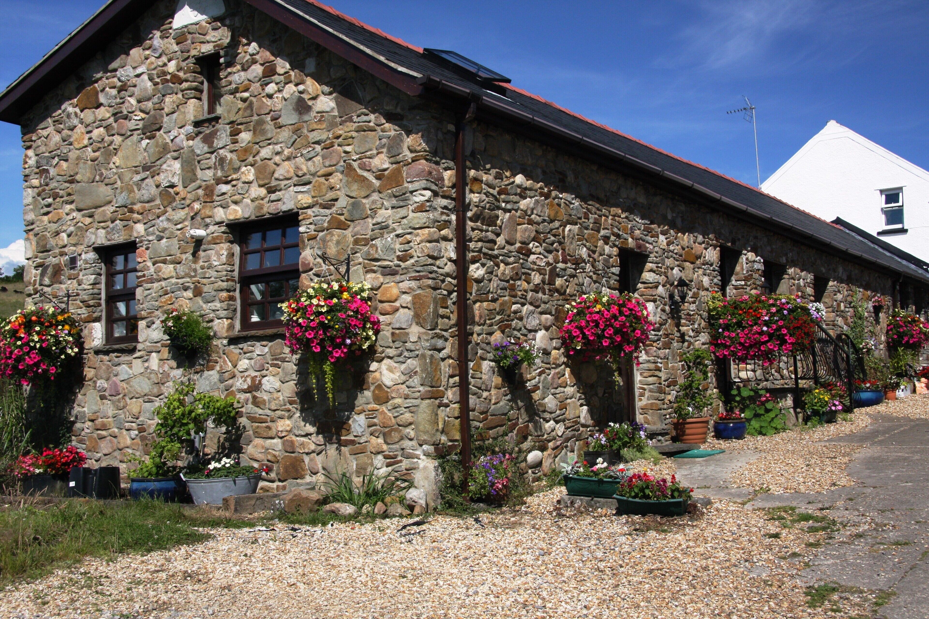 A stone building with multiple flower boxes and a gravel driveway.