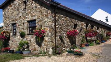 A stone building with multiple flower boxes and a gravel driveway.