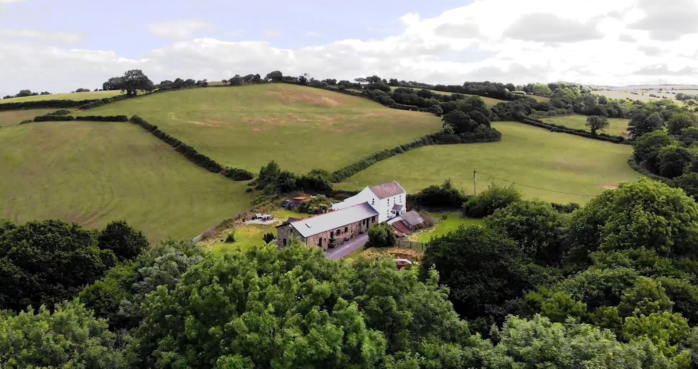 A rural property with a large house surrounded by fields and trees.