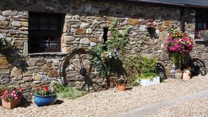 Un edificio in pietra con una finestra, una ruota e diversi vasi con piante.