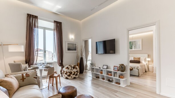 Un salon moderne comprenant un canapé, des poufs, une table à manger et un téléviseur.