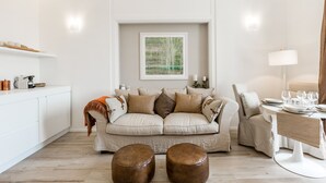 Un salon moderne comprenant un canapé, des poufs, une table basse et un coin repas avec une lampe.