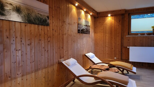 Una habitación con paneles de madera, dos sillones reclinables, un radiador y una ventana con persianas.