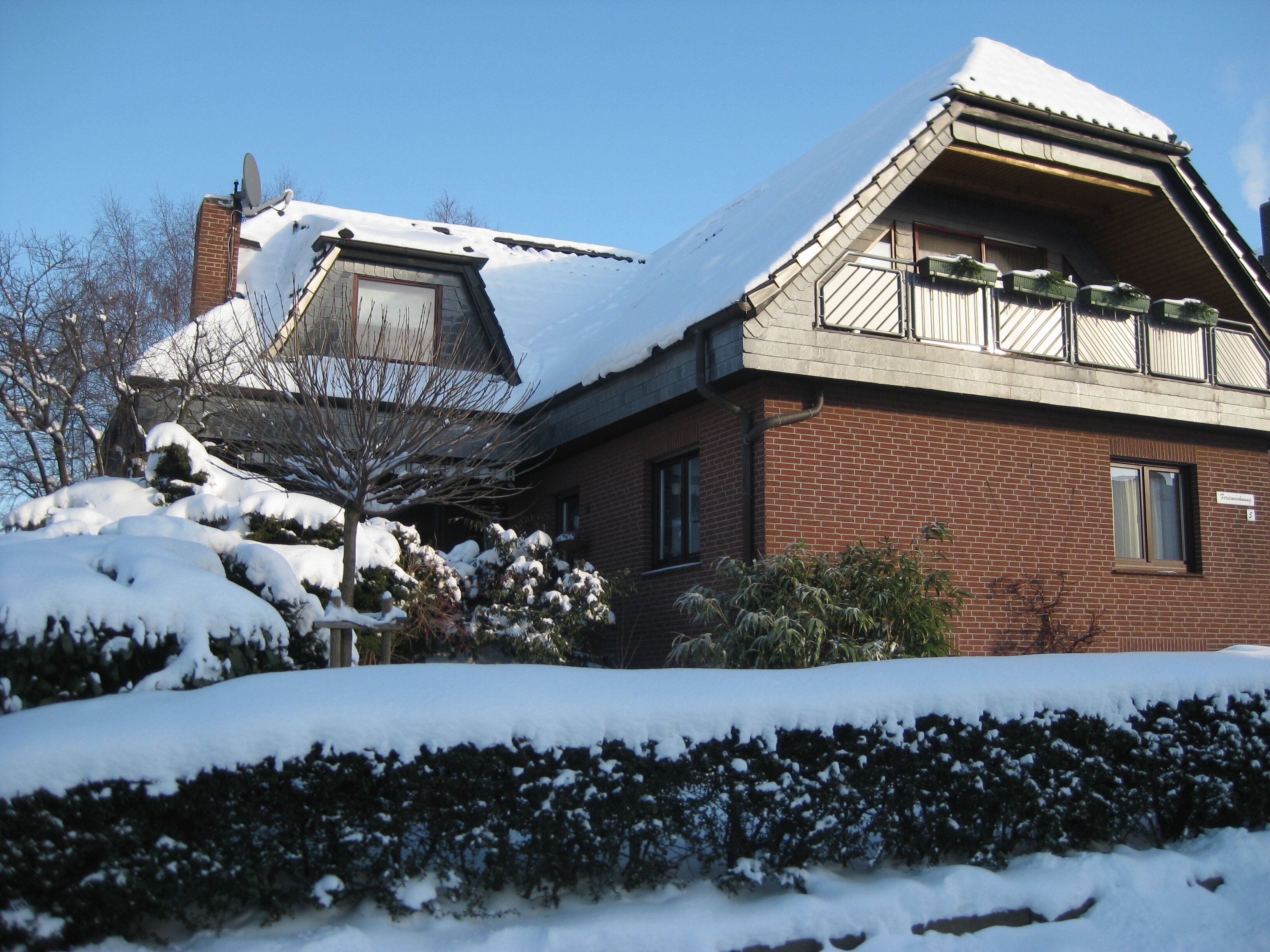 Una casa de dos pisos con techo nevado y fachada de ladrillo.