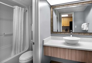 Ein Badezimmer mit Badewanne, Toilette und Waschbecken mit Spiegel darüber.