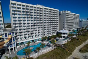 Ein großes Hotel mit mehreren Etagen, einem Schwimmbad und einem Strandbereich.