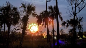 Atardecer con palmeras en primer plano y una vista distante de un pueblo.