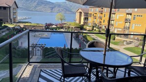 A balcony with a pool, outdoor seating, and a view of a lake and mountains. - Barona Beach Lakefront Luxury in front of world class wineries (West Kelowna)