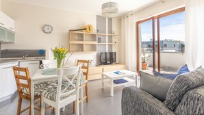 Ein modernes Wohnzimmer mit einer Couch, einem Esstisch mit Stühlen, einem Fernseher und einem Bücherregal.