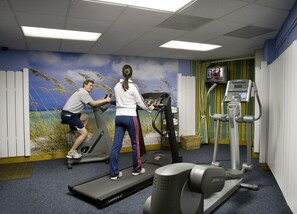 Ein Fitnessraum mit Laufbändern, einem Ergometer und einem Wandgemälde.