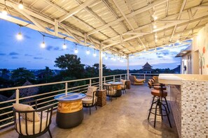 An outdoor terrace with seating and a bar area, overlooking a scenic landscape. - Modern, Deluxe Room with pool view #2 (Mengwi)
