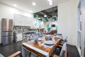 A modern kitchen with a dining area, featuring a large wooden table, white cabinets, and a tiled backsplash. - Modern, Deluxe Room with pool view #2 (Mengwi)