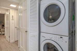 A laundry area with stacked washing machines and a door leading to another room.