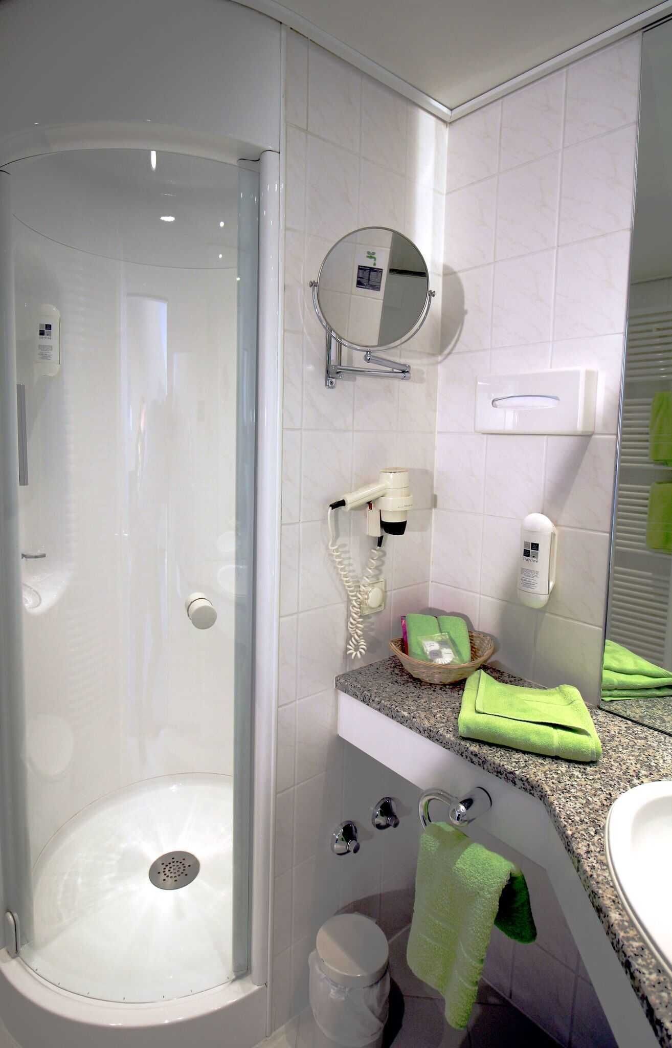 A modern bathroom with a glass-enclosed shower, a sink with a granite countertop, and a mirror above the sink.