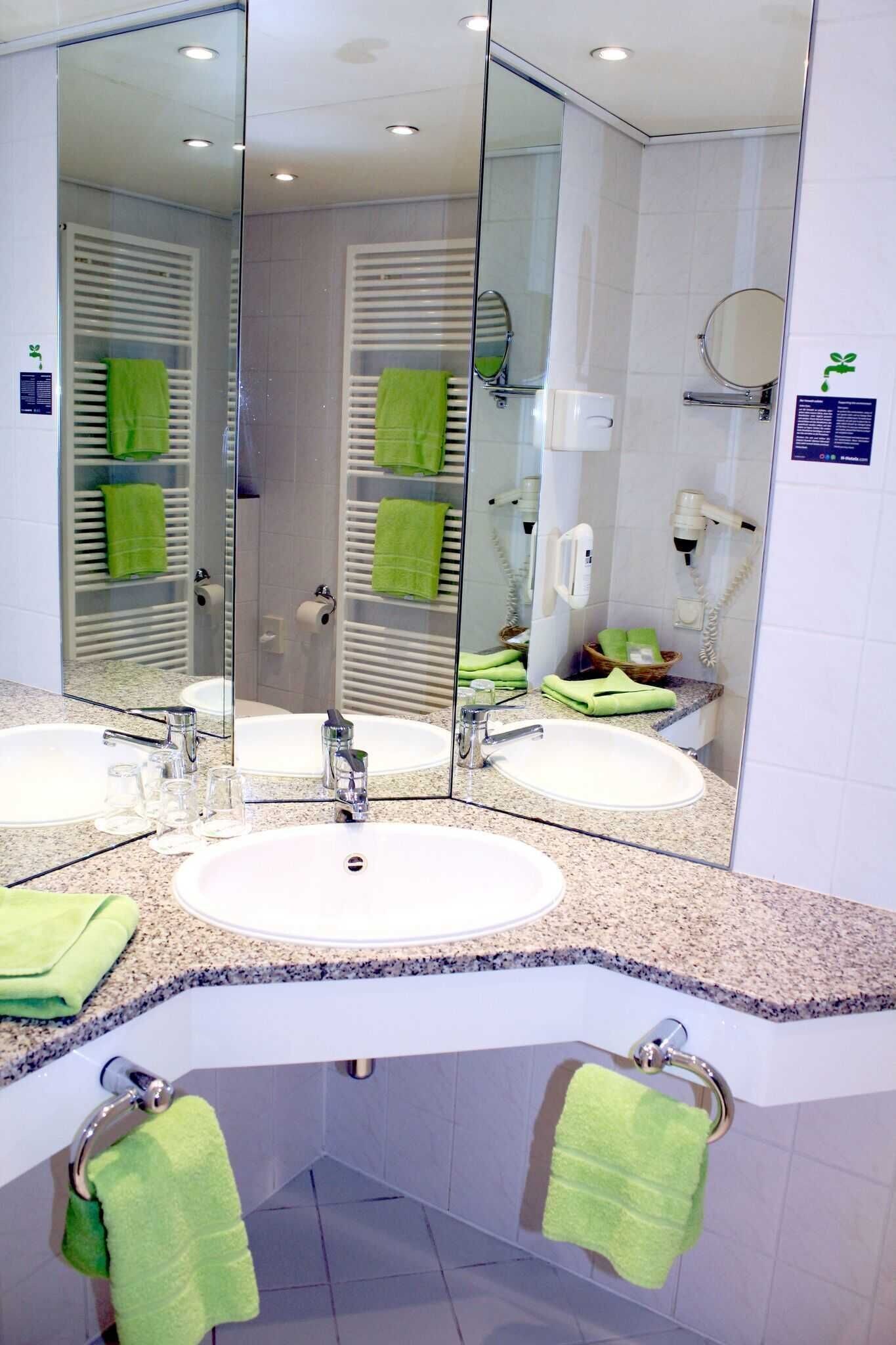 Ein Badezimmer mit zwei Waschbecken, einem großen Spiegel und einer Duschkabine aus Glas.