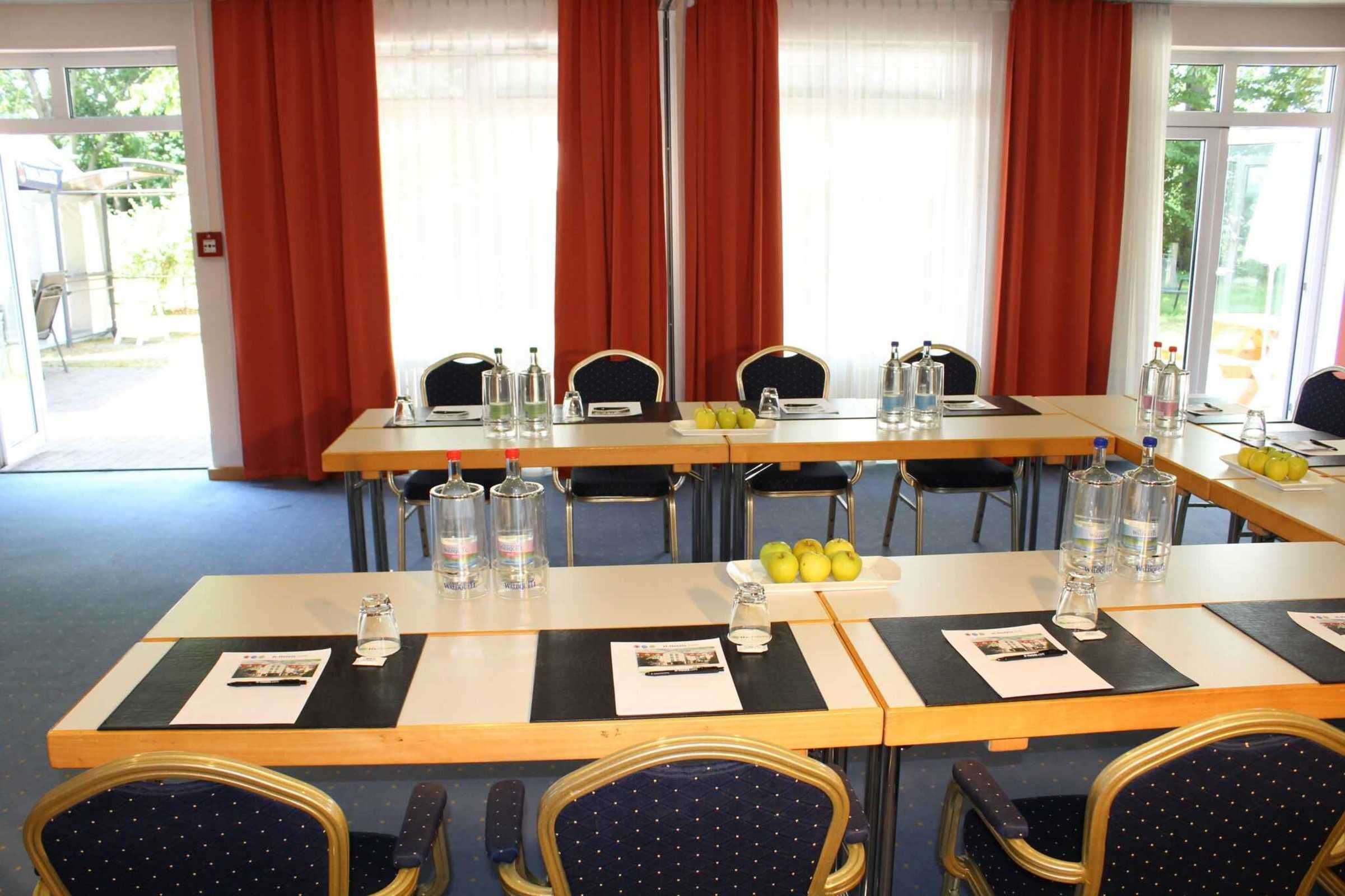 A conference room with tables set for meetings, equipped with water bottles, glasses, and nameplates.