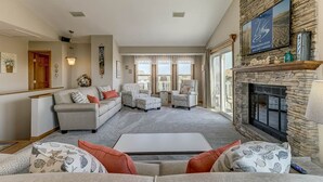 A spacious living room with a stone fireplace, comfortable seating, and large windows. - A Sitting Duck | 460 ft from the beach | Duck (Duck)