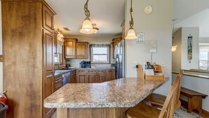 A kitchen with wooden cabinets, granite countertops, and pendant lighting. - A Sitting Duck | 460 ft from the beach | Duck (Duck)