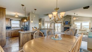 A spacious kitchen with wooden cabinets, a central island, and a dining area with a large wooden table and chairs. - A Sitting Duck | 460 ft from the beach | Duck (Duck)