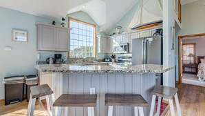 Cozinha com uma ilha grande, banquetas e vista para o exterior.