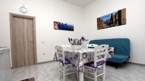 Un comedor con una mesa preparada para dos personas, un sofá azul y dos cuadros en la pared.