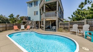 Une maison à deux étages avec une piscine, du mobilier d’extérieur et une terrasse en bois.