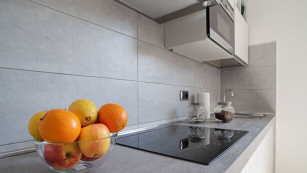 A kitchen with a glass bowl of fruit, a microwave, and a coffee maker on the counter. - GuestHost - The apartment is located in a quiet area, in a closed / private street overlooking the green and private gardens.It is located in a strategic position, a few steps from the historic center (the main road is located in absolute proximity to on (Bologna)