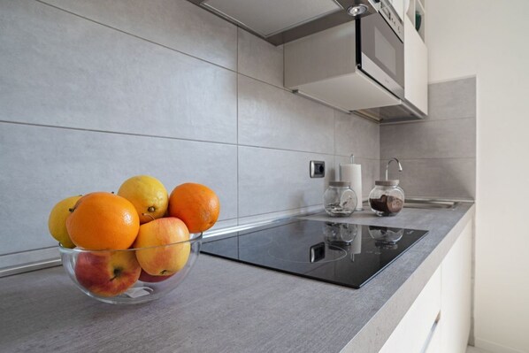 A kitchen with a glass bowl of fruit, a microwave, and a coffee maker on the counter.