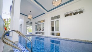 A pool area with a blue-tiled floor, a metal handrail, and a staircase leading to an upper level. - hung hoang villa hoi an (Tp. Hội An)
