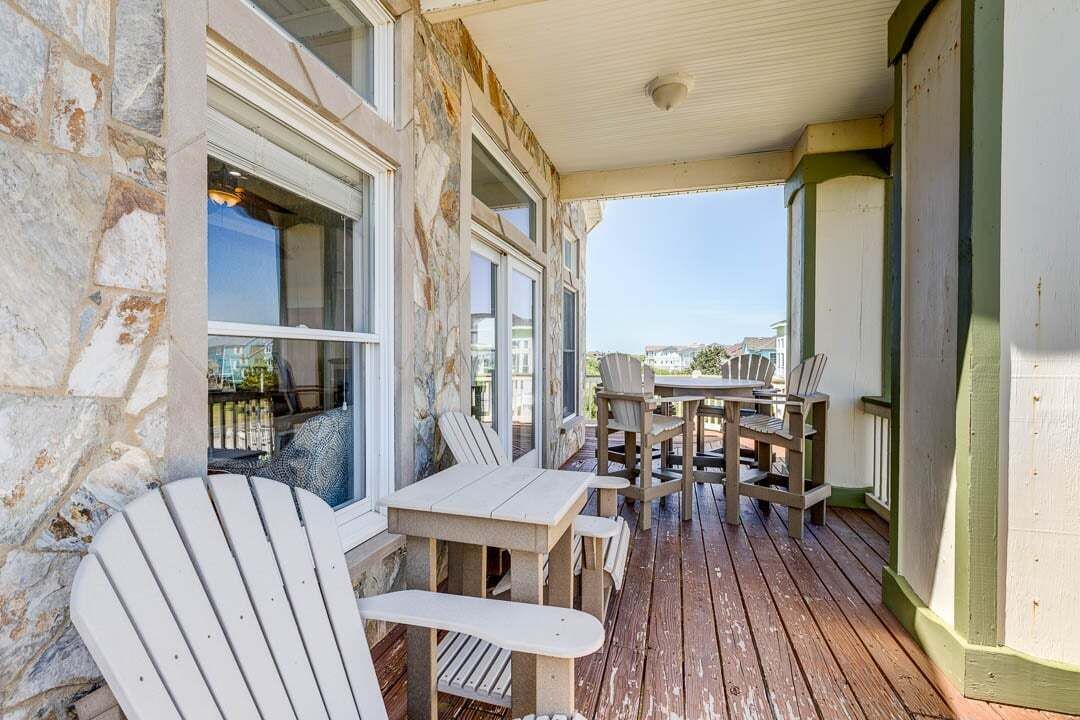 A covered outdoor seating area with Adirondack chairs and a table, stone walls, and a view of the surrounding area.